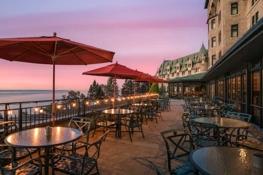 Outdoor patio and dining area in front of a large stone building with green roofing