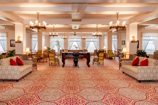 Large banquet hall with cushioned chairs and a piano in the center