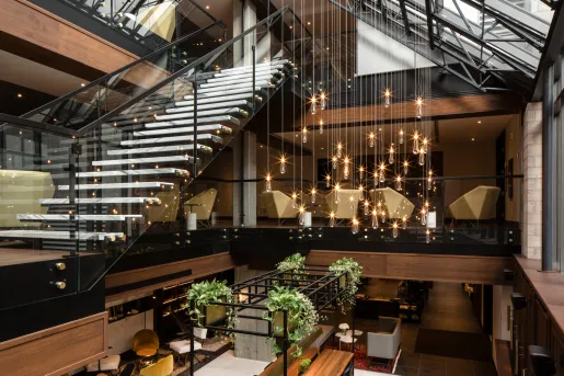 Hotel lobby with a staircase with glass walls and hanging lights