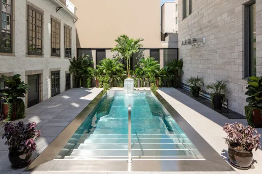 Outdoor pool with a small fountain and green plants in the back