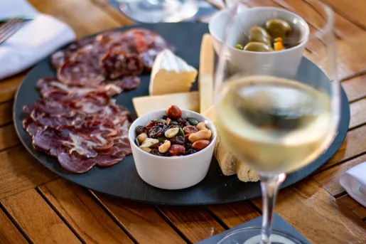 Plate with cured meats, nuts and cheese next to a glass of wine