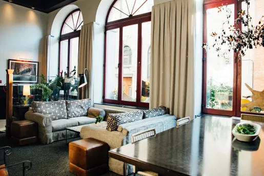 Seating and lounge area with large windows and tall curtains