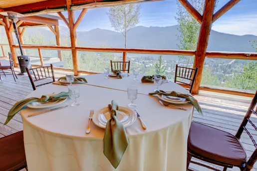 Circular dining table on an outdoor patio, overlooking a small town and tall trees