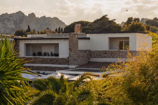 Exterior view of white and stone building with trees in front