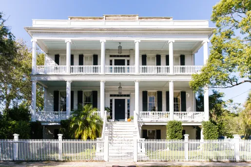 Exterior view of two-story white building with a white fence