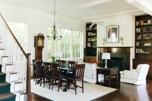 Living room with a wooden dining table over a white rug, and a fireplace to the right