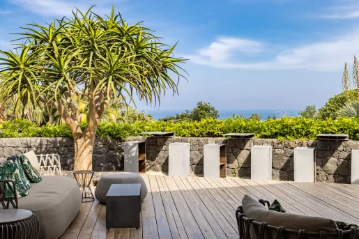 Outdoor patio with cushioned, gray chairs and cement stools and tables