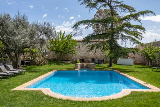 Outdoor pool with a large grass field and tall trees in the back