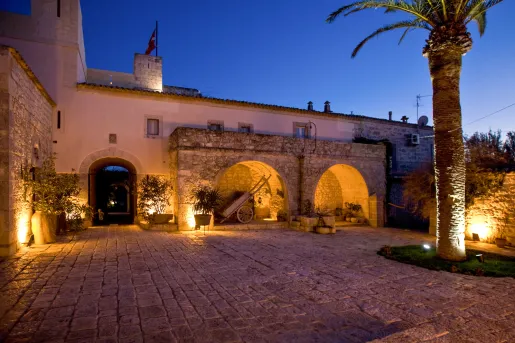 Exterior view of large stone and brick building with an illuminated courtyard