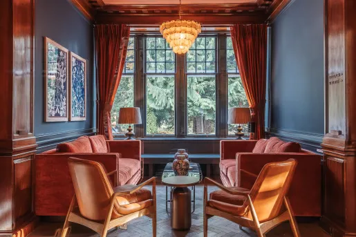 Seating area with cushioned, red sofas with large windows in the background