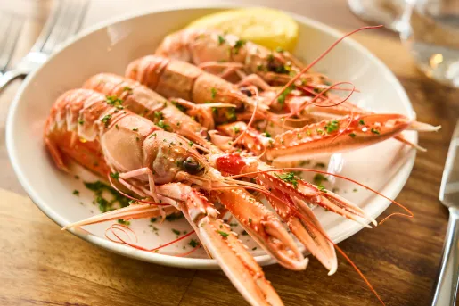 Plate of cooked prawns with a lemon wedge on the right