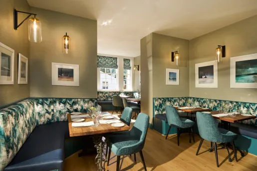 Dining hall with blue and green chairs and sofas around tables