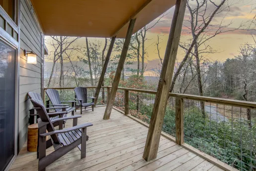 Outdoor patio of a wooden cabin, looking out towards a forest