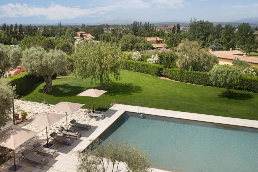 Outdoor pool surrounded by reclining chairs and a large grass area
