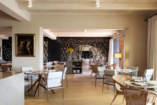 Hotel restaurant dining hall with woven chairs and square and circular tables
