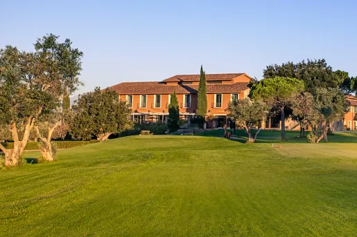 Large grass lawn leading to an orange, two-story building