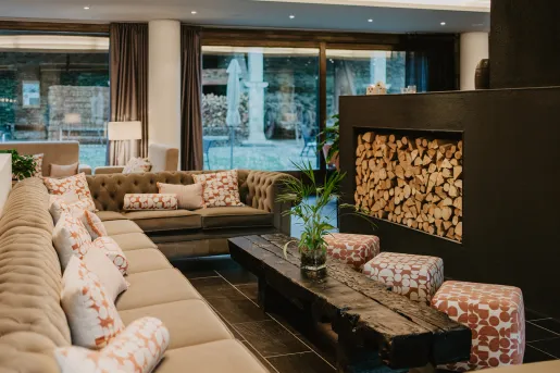 Hotel lobby with cushioned sofas in front of a large, black fireplace