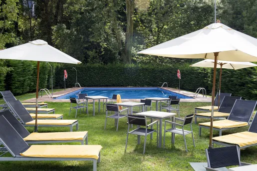 Outdoor pool with reclining chairs and umbrellas on a grass field