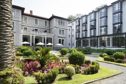 Exterior view of white, black and gray stone hotel building with a garden in front