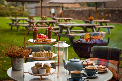 Table outdoor with tea and pastries, with benches in the background