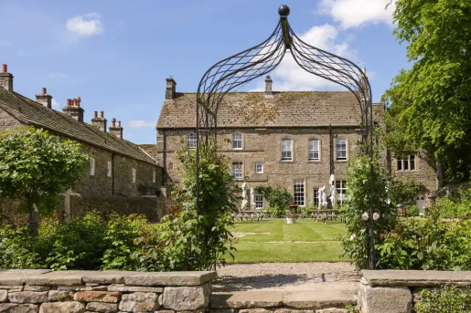 Outdoor view of a stone building with a large grass field and large umbrellas