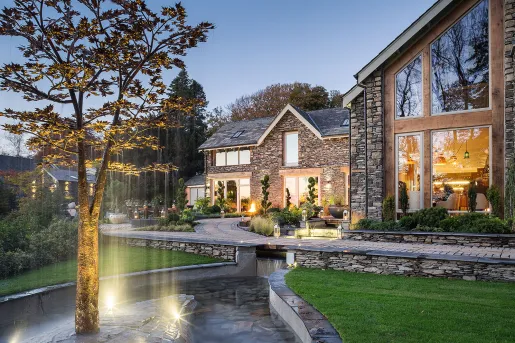Exterior view of stone house with a fountain and tree in front