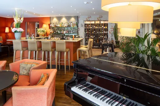 Bar and lounge with an alcohol rack in the back and a piano in front