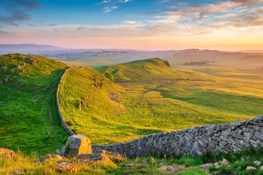 Large stone wall across a large, grassy hill