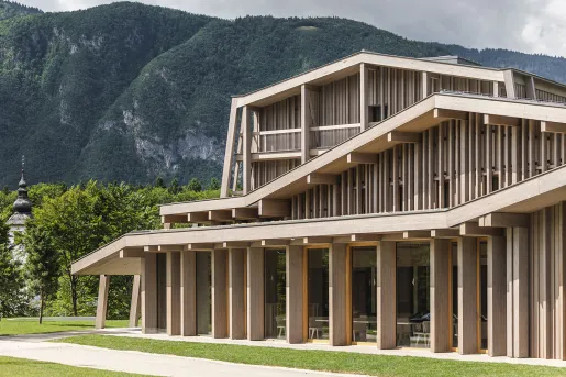 Exterior view of wooden building with tree-covered hills in the background
