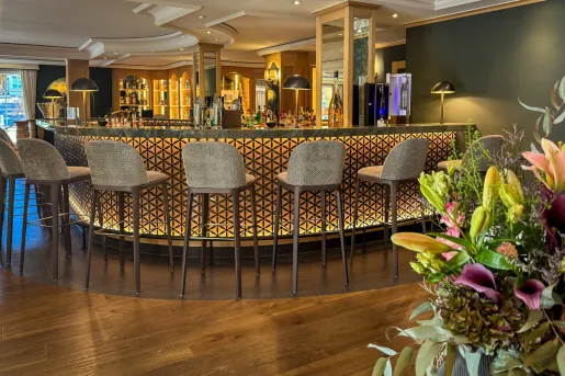 Bar and lounge with an illuminated bar and beige stools in front