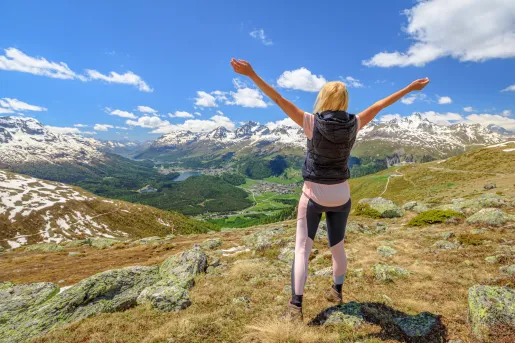 Woman standing on top of a hill with her arms open