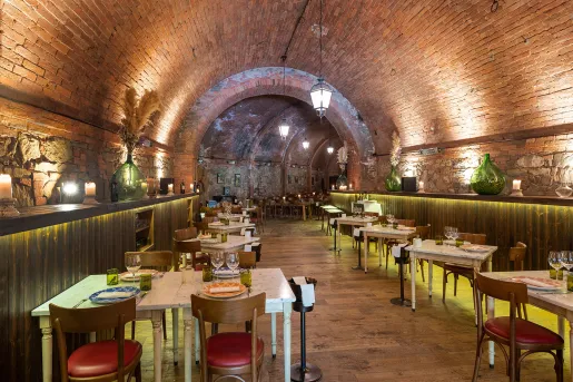 Long tunnel restaurant with brick walls and square dining tables