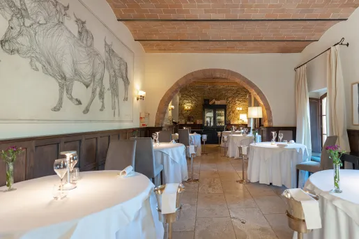 Restaurant dining room with circular tables and paintings on bulls on the wall to the left