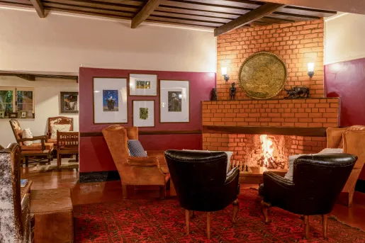 Leather chairs surrounding a brick fireplace, with paintings on the walls