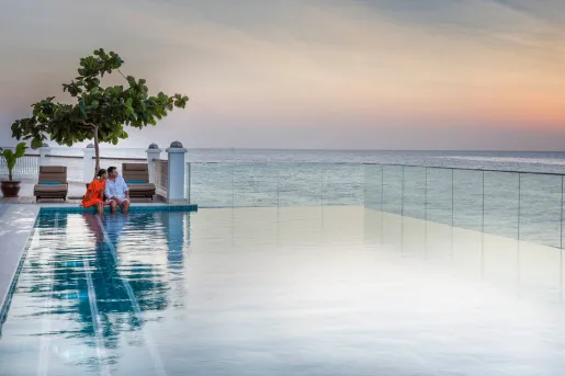 Outdoor infinity pool, with man and woman sitting with their feet in the pool