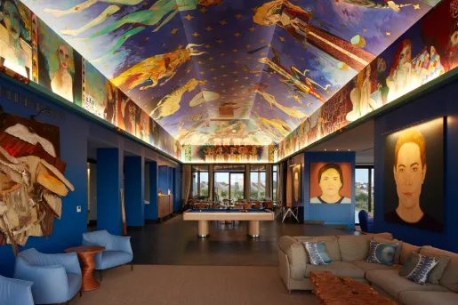 Long, blue room with murals on the ceiling and the walls, with couches along the room