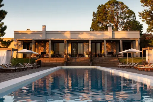 View of outdoor pool with a large, white building in the back
