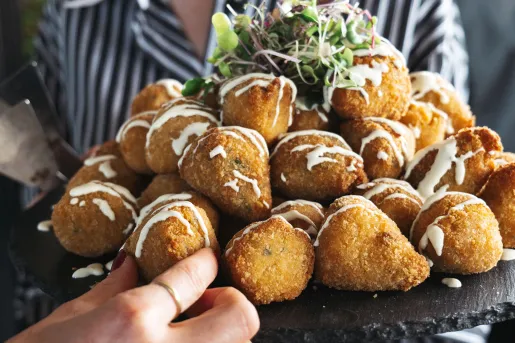 Person holding a large plate of fried food