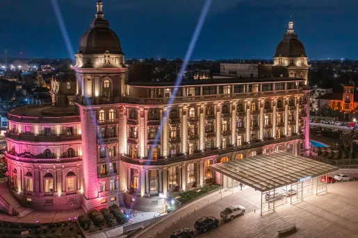 Exterior view of European-style hotel building, illuminated by bright pink and white lights