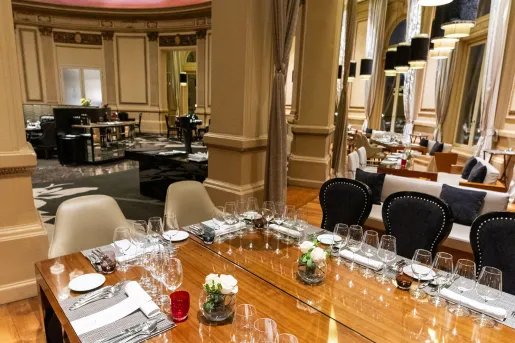 Dining hall area with wooden tables and wine glasses on each table