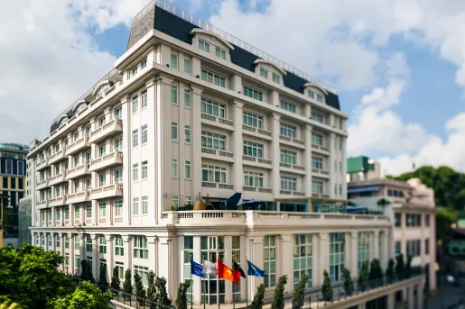 Daytime, exterior view of white multi-story building with flags in front