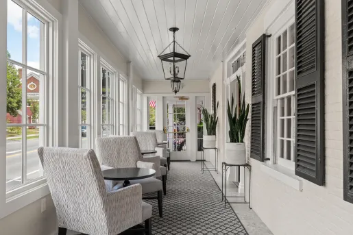 Hallway with potted plants and cushioned, white chairs