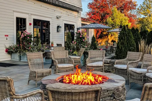 Outdoor firepit with woven chairs surrounding it in a circle