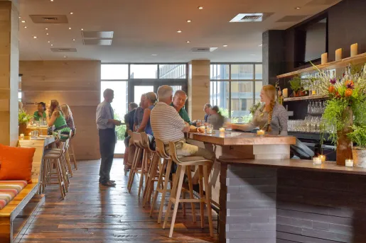 Bar with groups of people sitting at the counter, grabbing drinks from the bartender
