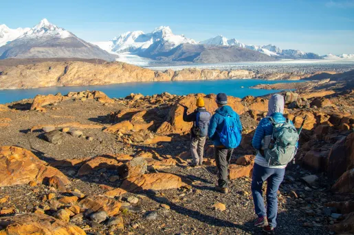 Three people walking on gravel trails towards a lake
