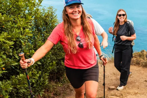 Two women with walking poles ascending a sandy path