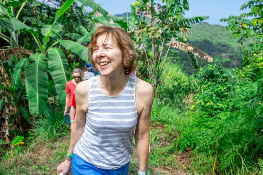Woman smiling while ascending a trail surrounded by tall plants