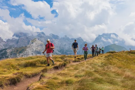 Group of people descending a dirt trail in the middle of a valley
