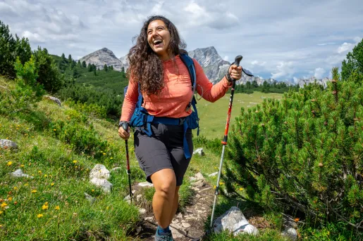 Woman smiling while walking through a grassy trail