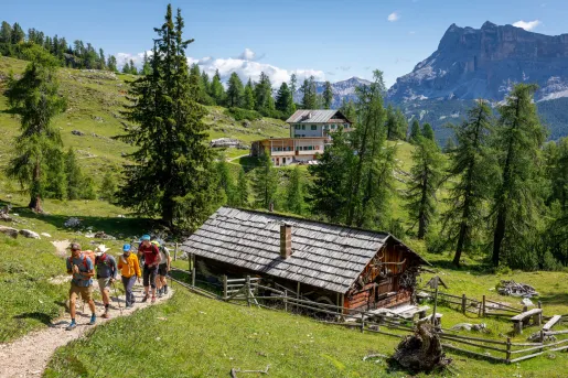 Wooden cabin with a group of people hiking to the left
